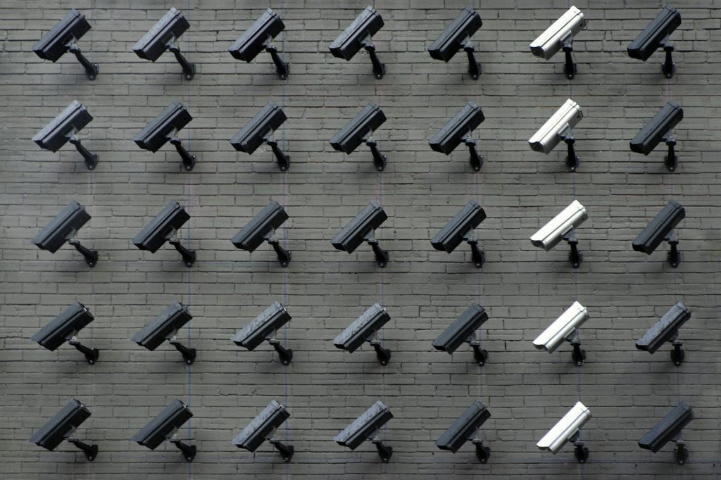 Rows of security cameras mounted on a grey brick wall