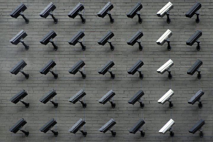 Rows of security cameras mounted on a grey brick wall