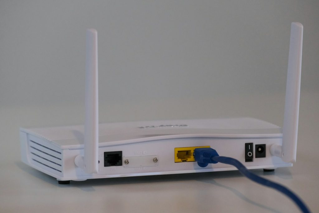 White wireless router with antennas and a blue network cable