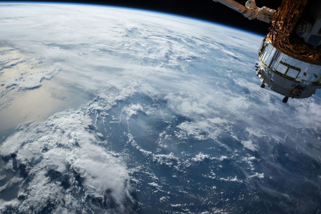 View of Earth and cloud cover from orbit, with part of a spacecraft in the frame